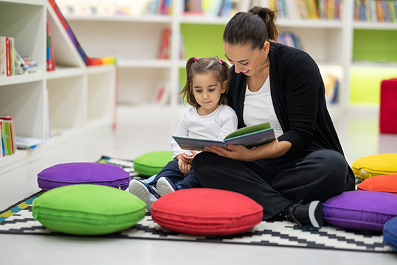 Pre-schooler and educator reading books in the classroom