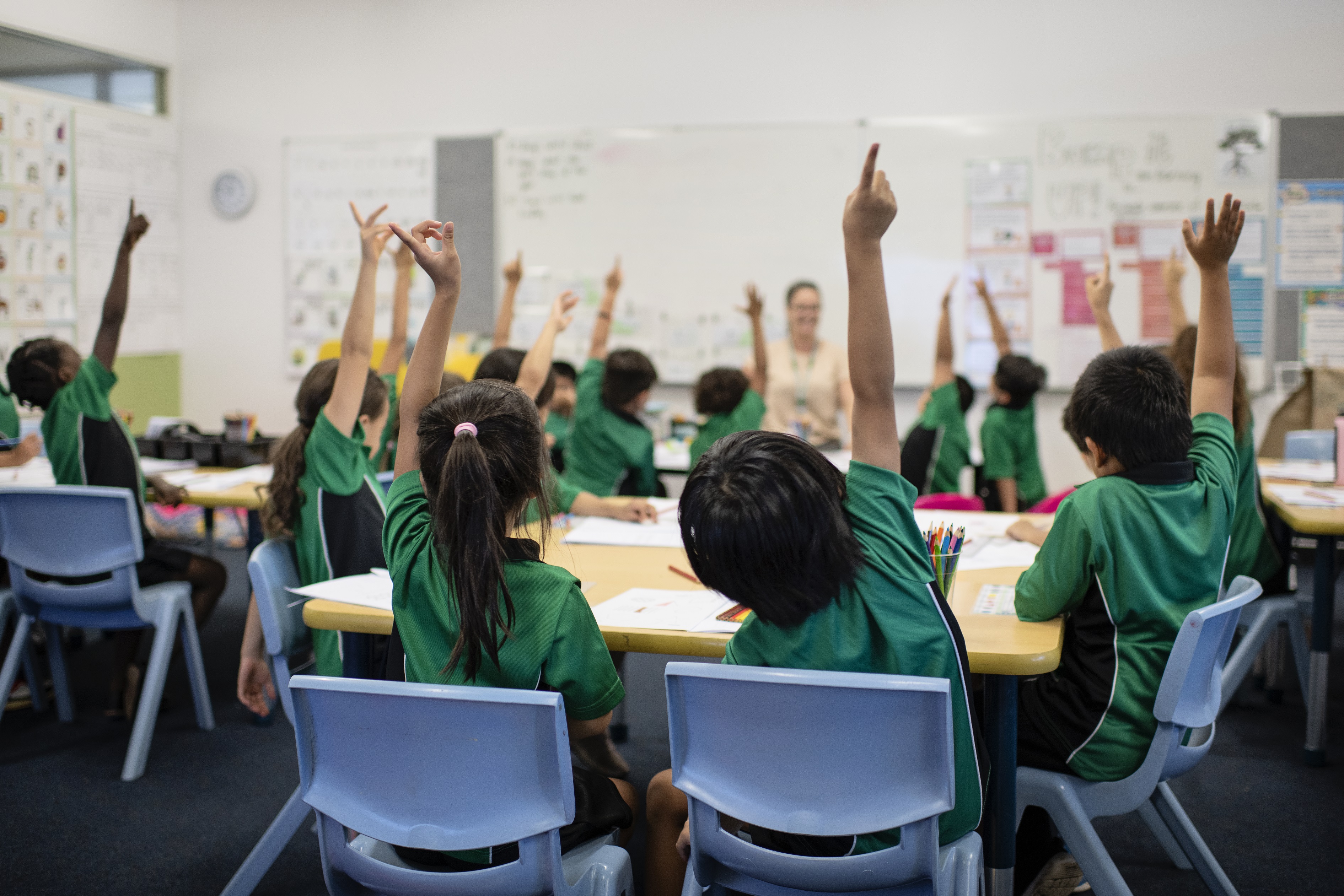 Children with their arms up in a classroom