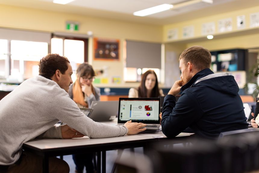 Teachers sit around an office table having a discussion
