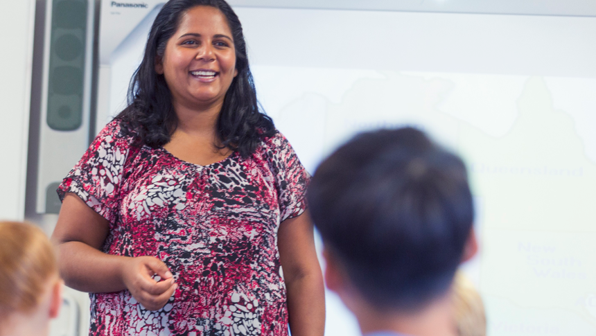 Female teacher smiling in front of class 