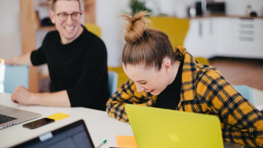 two adults working at laptops