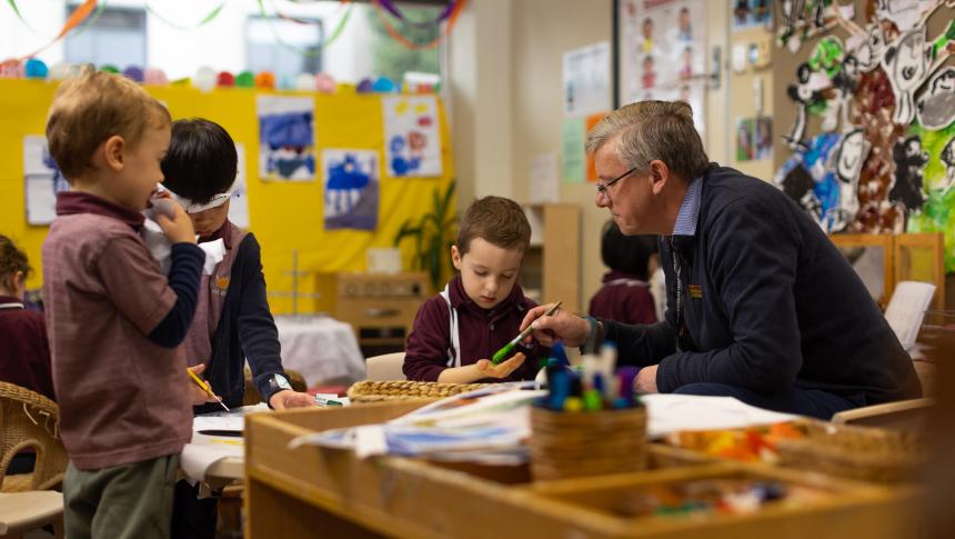 Adult sitting with 3 young students