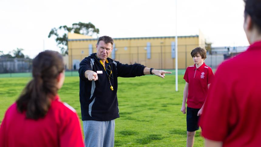 Teacher talking to students on a playing field