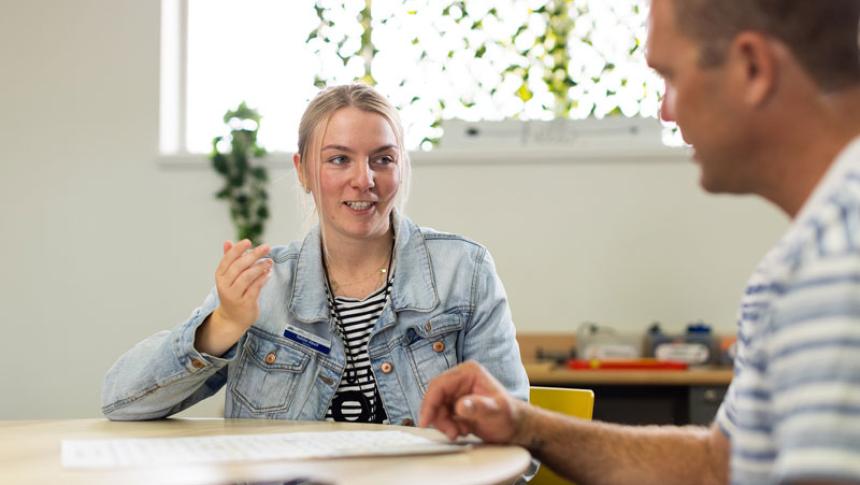 Two teachers sit at a table in conversation.