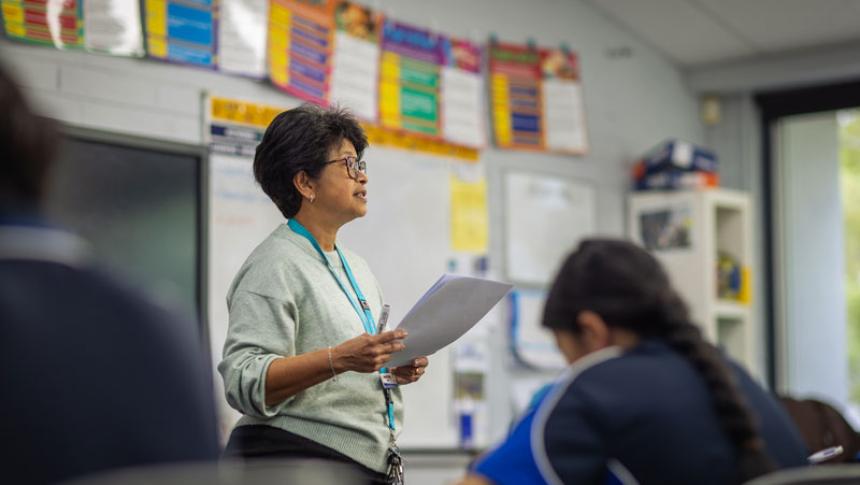A teacher surveys her class from the front of the room.