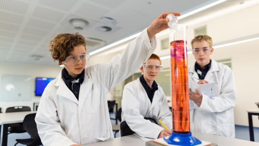Three students in a science lab performing an experiment. 