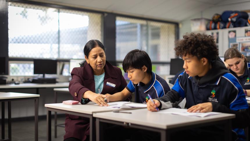 Teacher helping secondary school students with writing.