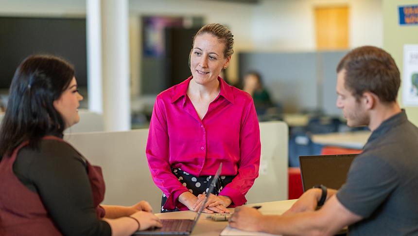 A teacher stands talking to two colleagues