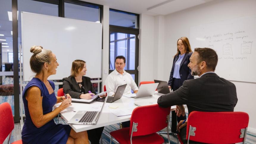 A group of teachers have a discussion around an office conference table