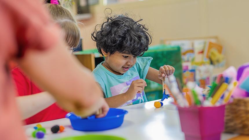 Young child playing with craft materials at table.