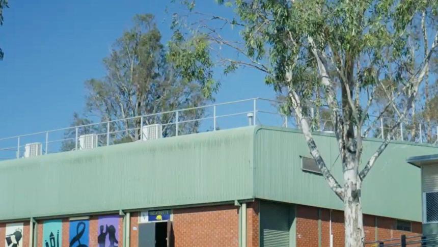 Outdoor photo of a school building with some mural style paintings on one of the walls