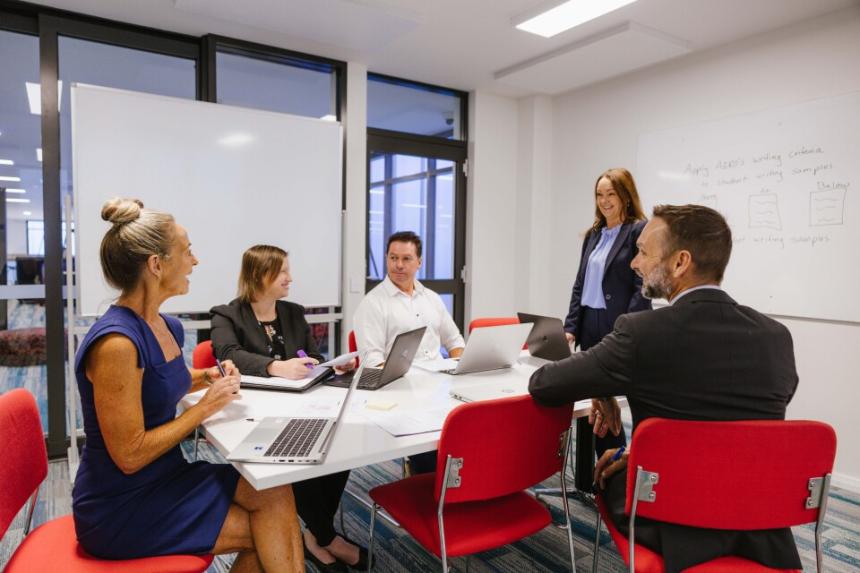 A group of teachers have a discussion around an office conference table