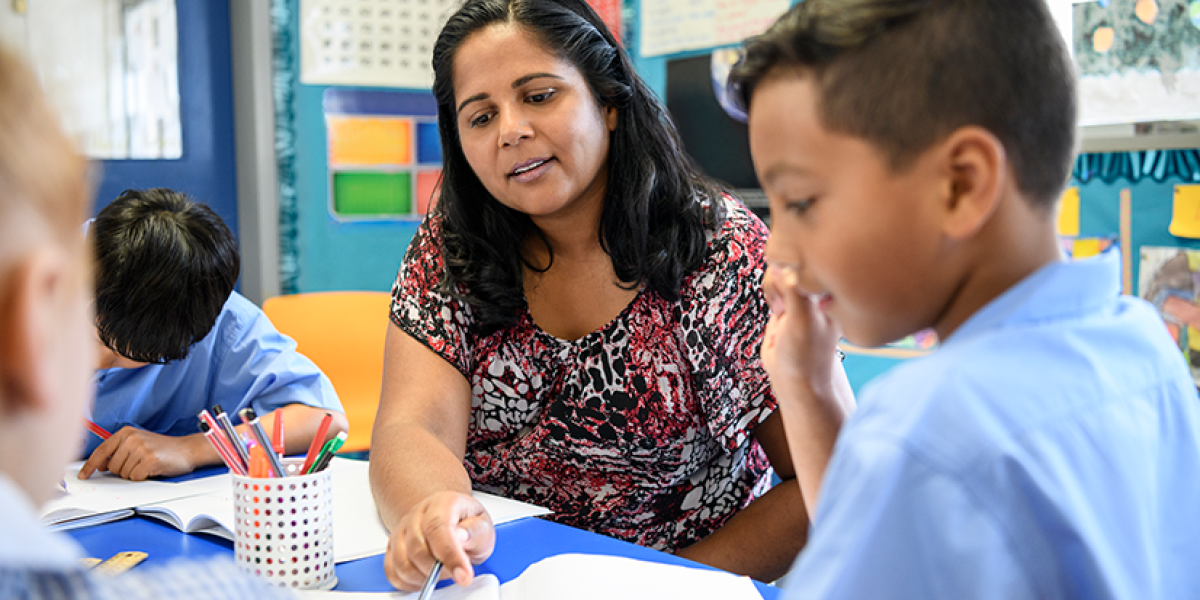 Australian female primary school teacher working with children offering support and guidance